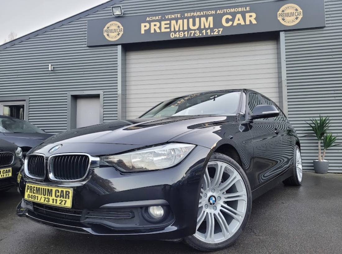 BMW Série 3 noire devant le garage